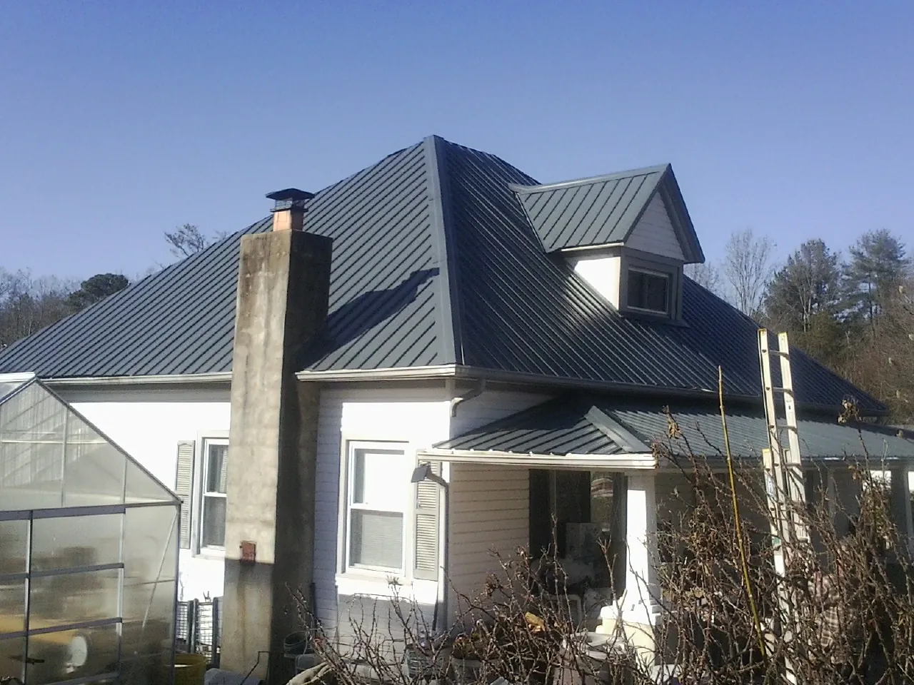 Dark blue standing seam metal roof on a white farmhouse with dormer — Slate & Tile Roof Repair by Roofing Brothers in New Matamoras