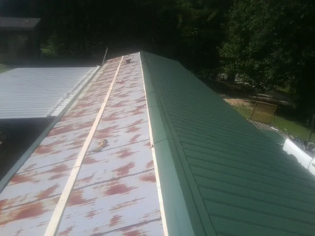 Old rusted panels beside newly installed green metal roofing — Wind Damage Roof Repair by Roofing Brothers in New Matamoras