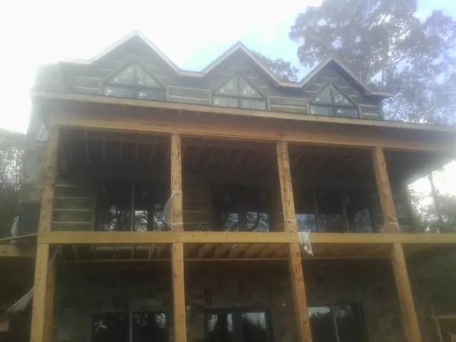 Dormers and porch framing on a large log home under construction — Roof Coating work by our crew in New Matamoras