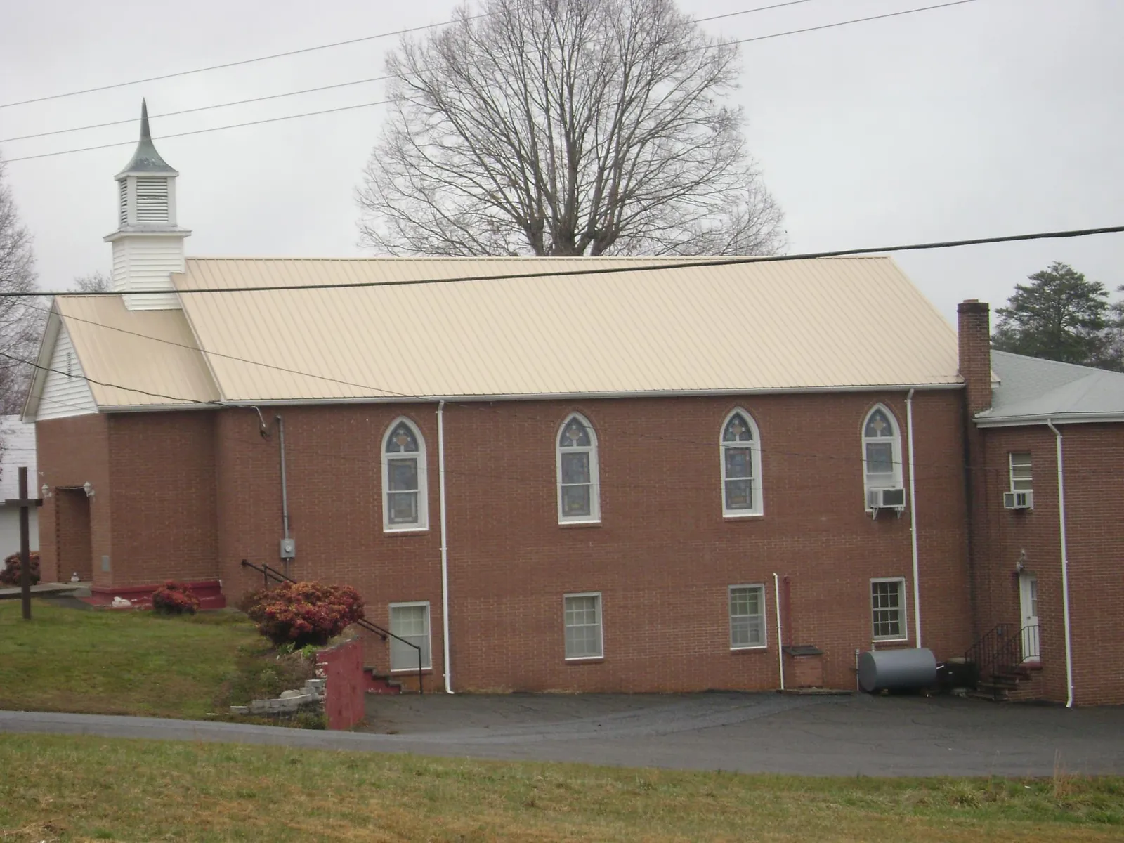 New tan metal roof on a brick church with a white steeple in New Matamoras