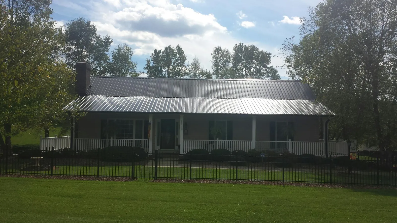 Gray metal roof on a brick ranch with a full width front porch — Gutter Guard Installation work by our crew in New Matamoras