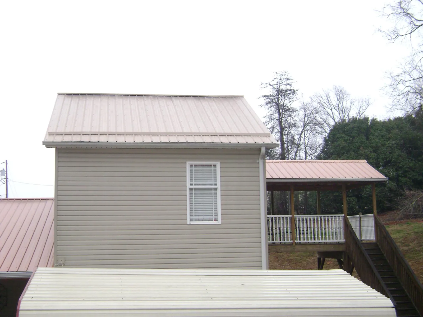 Tan metal roofs on a two story addition and attached porch, from a Roof Replacement job in New Matamoras