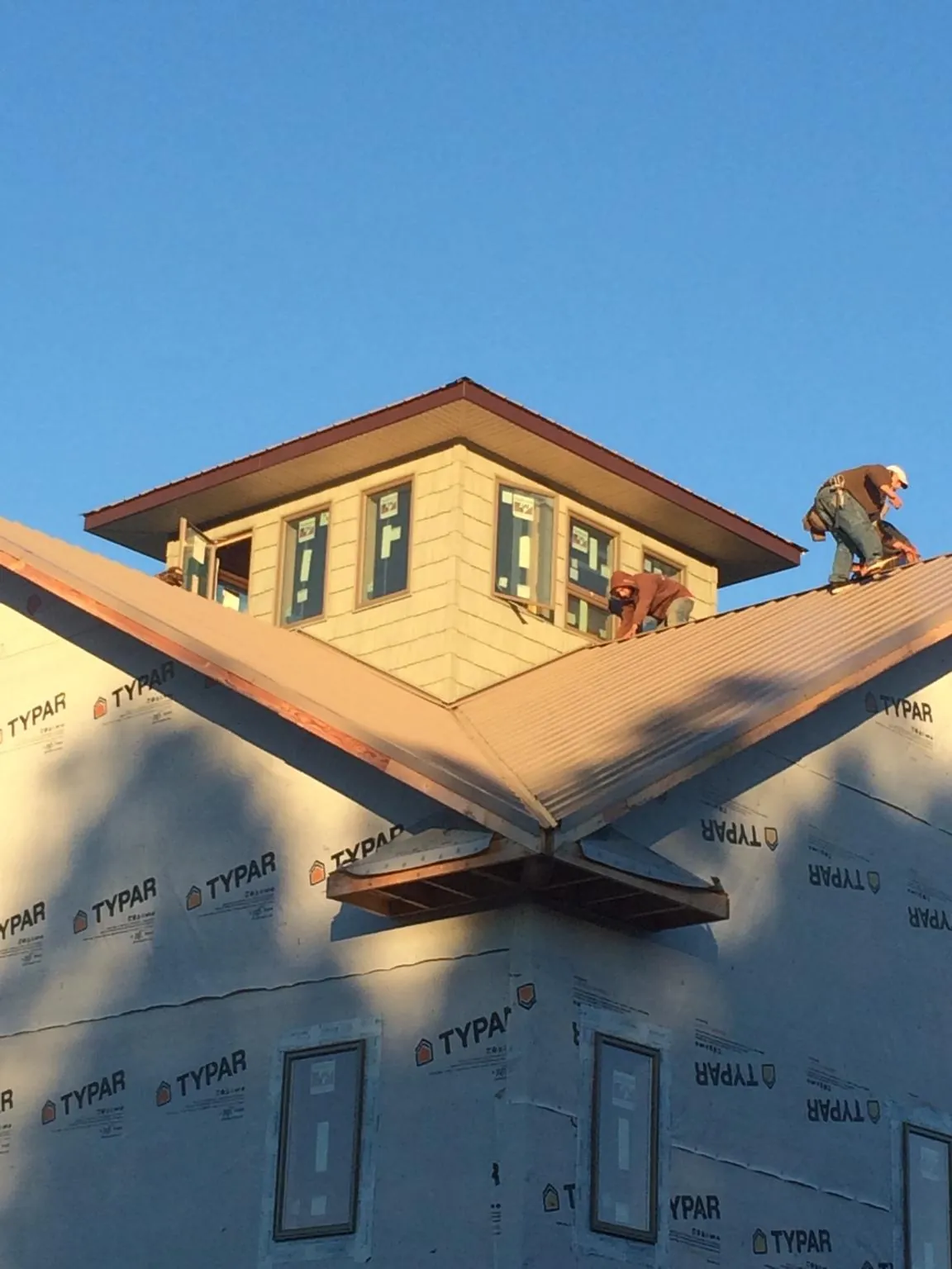 Roofers working around a rooftop cupola on a new metal roof at sunset — Roof Waterproofing in New Matamoras by Roofing Brothers